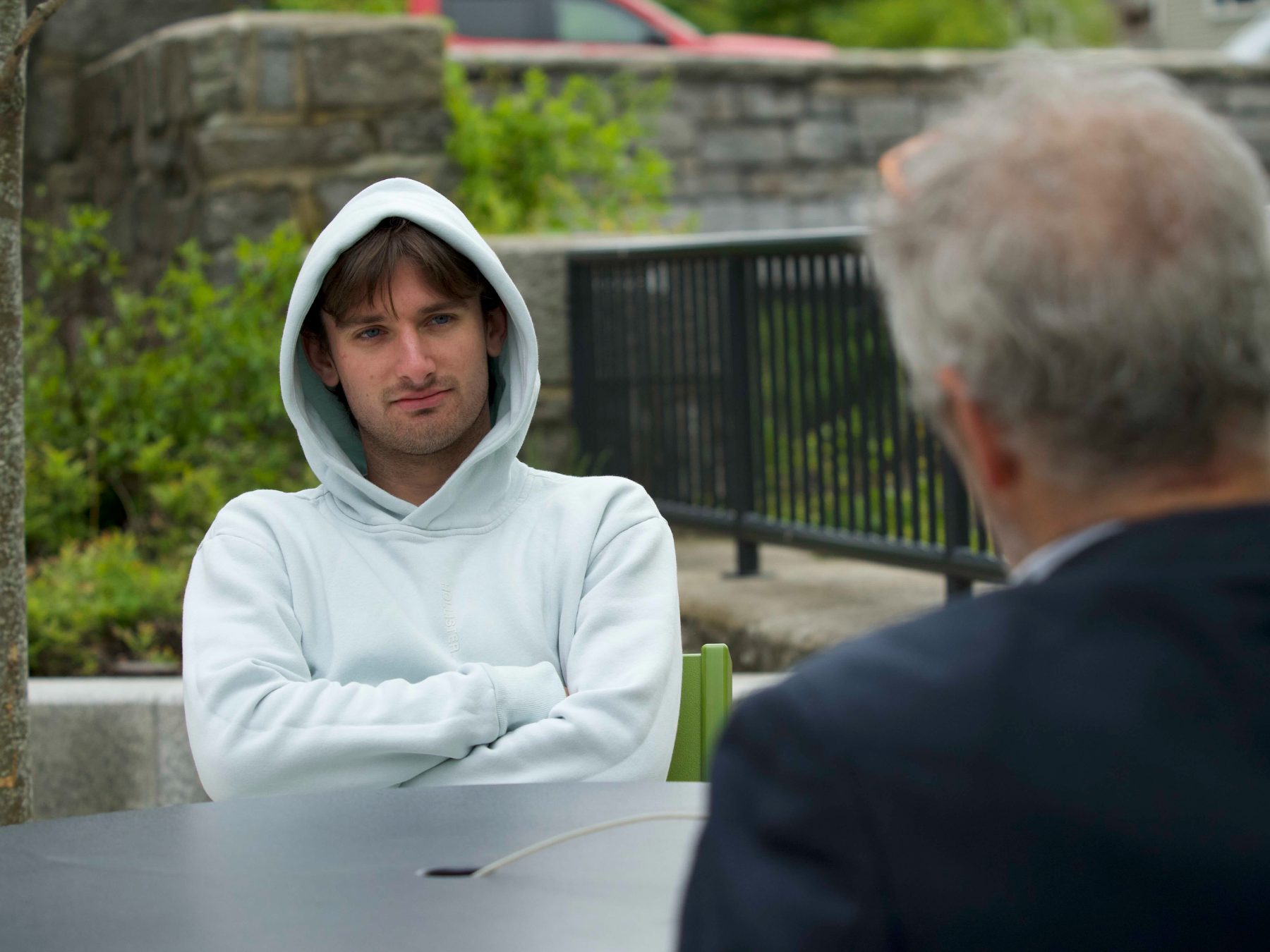 A young man in a hoodie talking with Jeff Levin outdoors