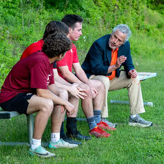 Jeff Levin talking with athletes on a bench